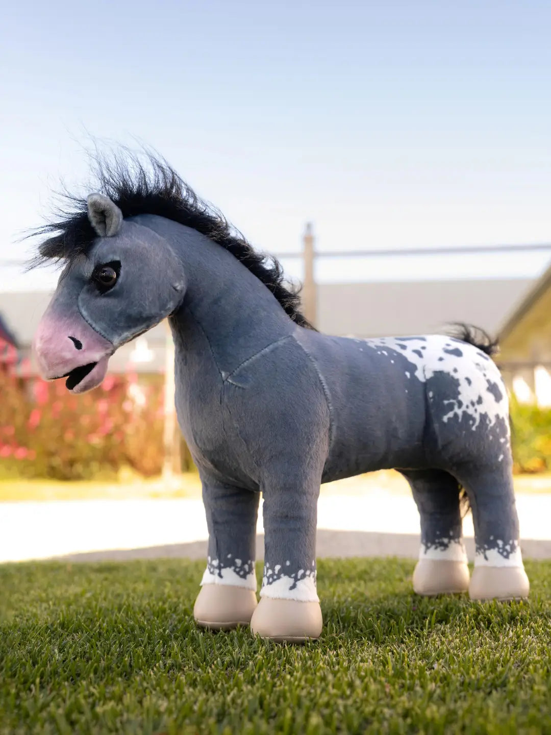 Side view of a stuffed animal gray appaloosa horse on grass