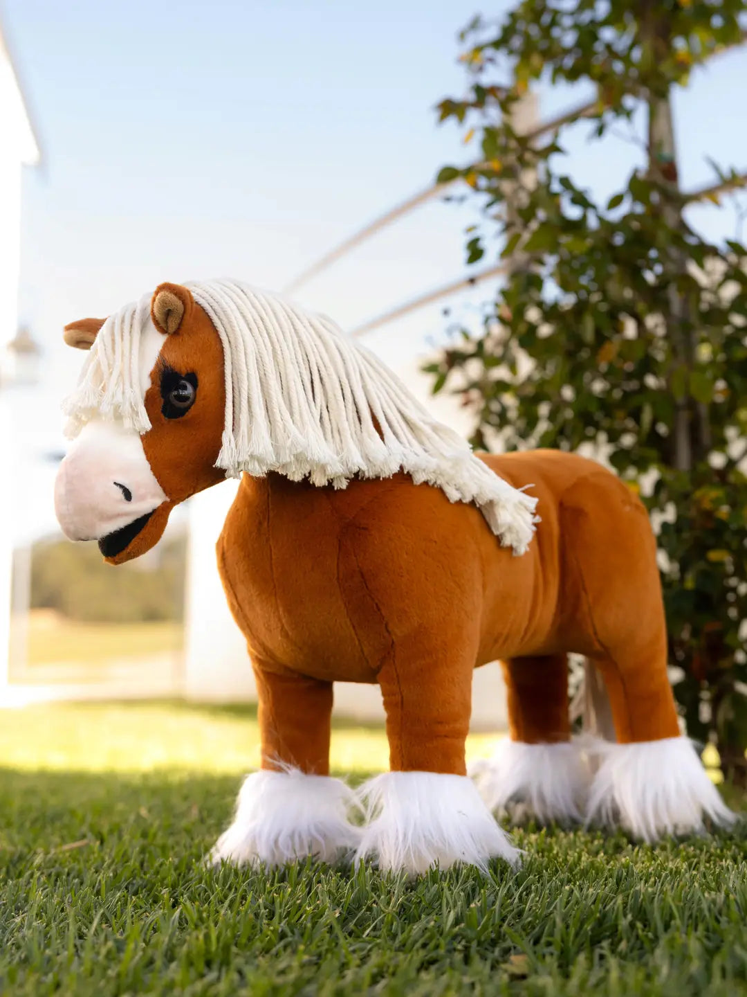 A palomino stuffed animal horse standing on grass