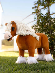A palomino stuffed animal horse standing on grass