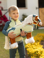 A young boy holding a stuffed animal toy horse, both wearing green and blue