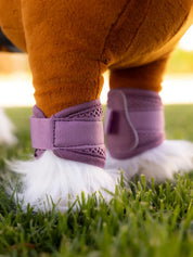 Toy pony standing outside wearing the LeMieux Toy Pony Mesh Brushing Boots in pink