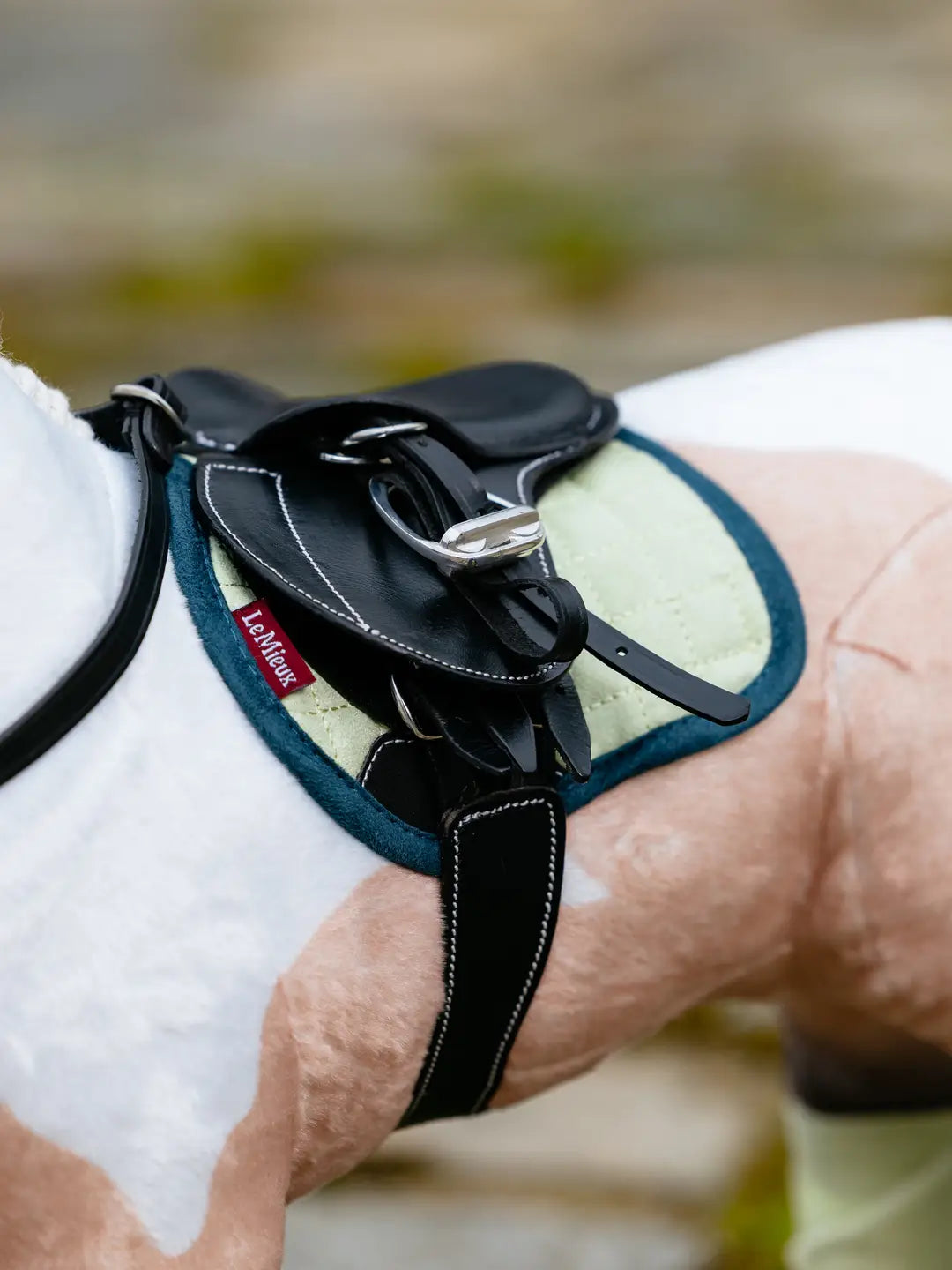 Close-up view of a buckskin paint toy pony wearing the green LeMieux Toy Pony Saddle Pad