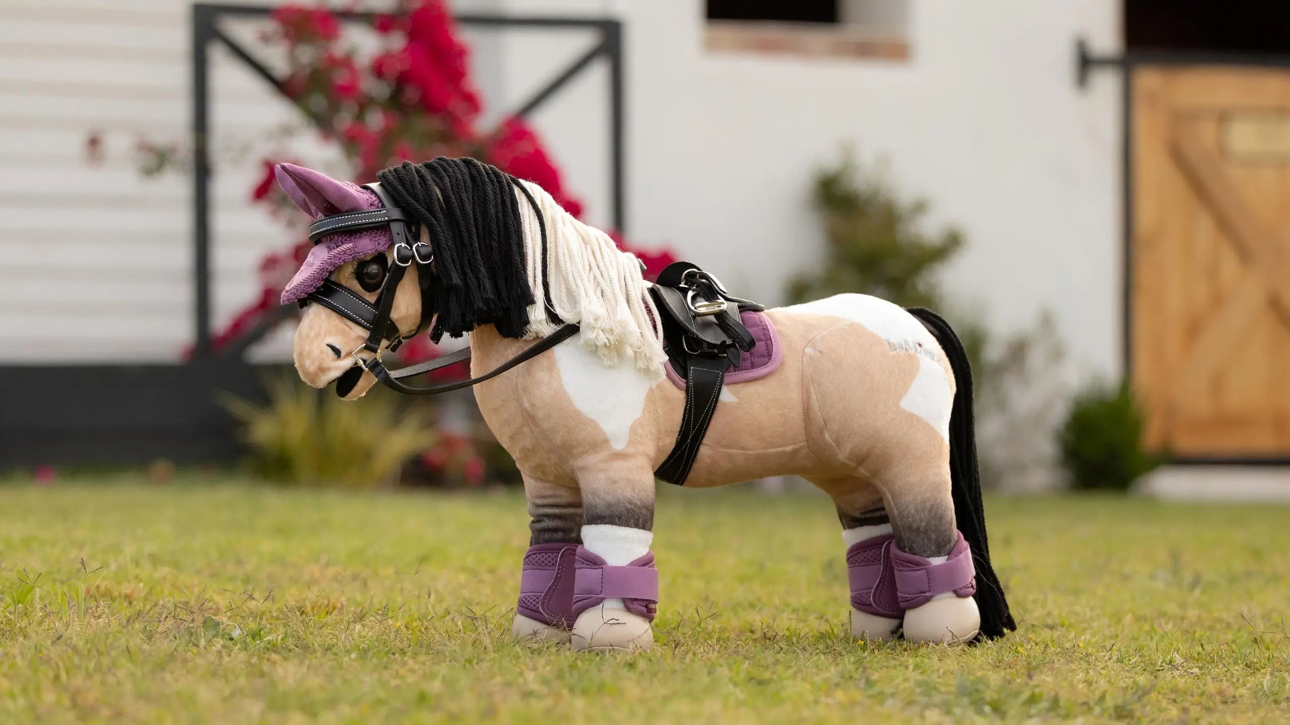Side view of a buckskin paint wearing the pink LeMieux Toy Pony Saddle Pad while standing in the grass