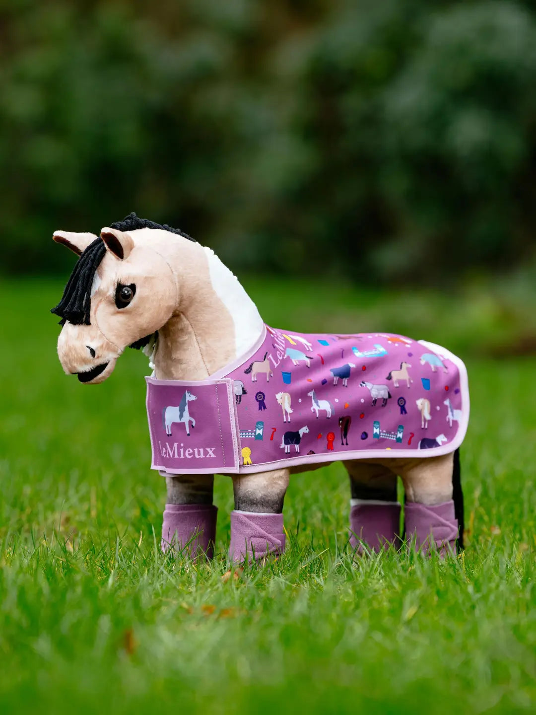 Stuffed animal horse standing outside wearing the LeMieux Toy Pony Printed Fleece Rug in pink