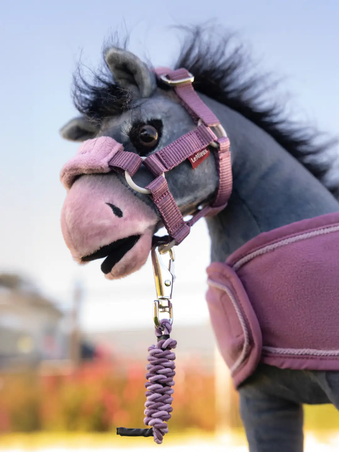 A stuffed animal toy horse standing outside wearing the Toy Pony Vogue Headcollar & Leadrope in pink