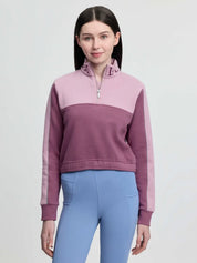 Front view of a young female model wearing the pink LeMieux Young Rider Cropped Kate Quarter Zip on a plain background