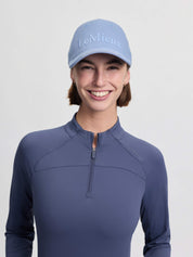 Front view of a female model wearing the powder blue LeMieux Lara Cap on a plain background