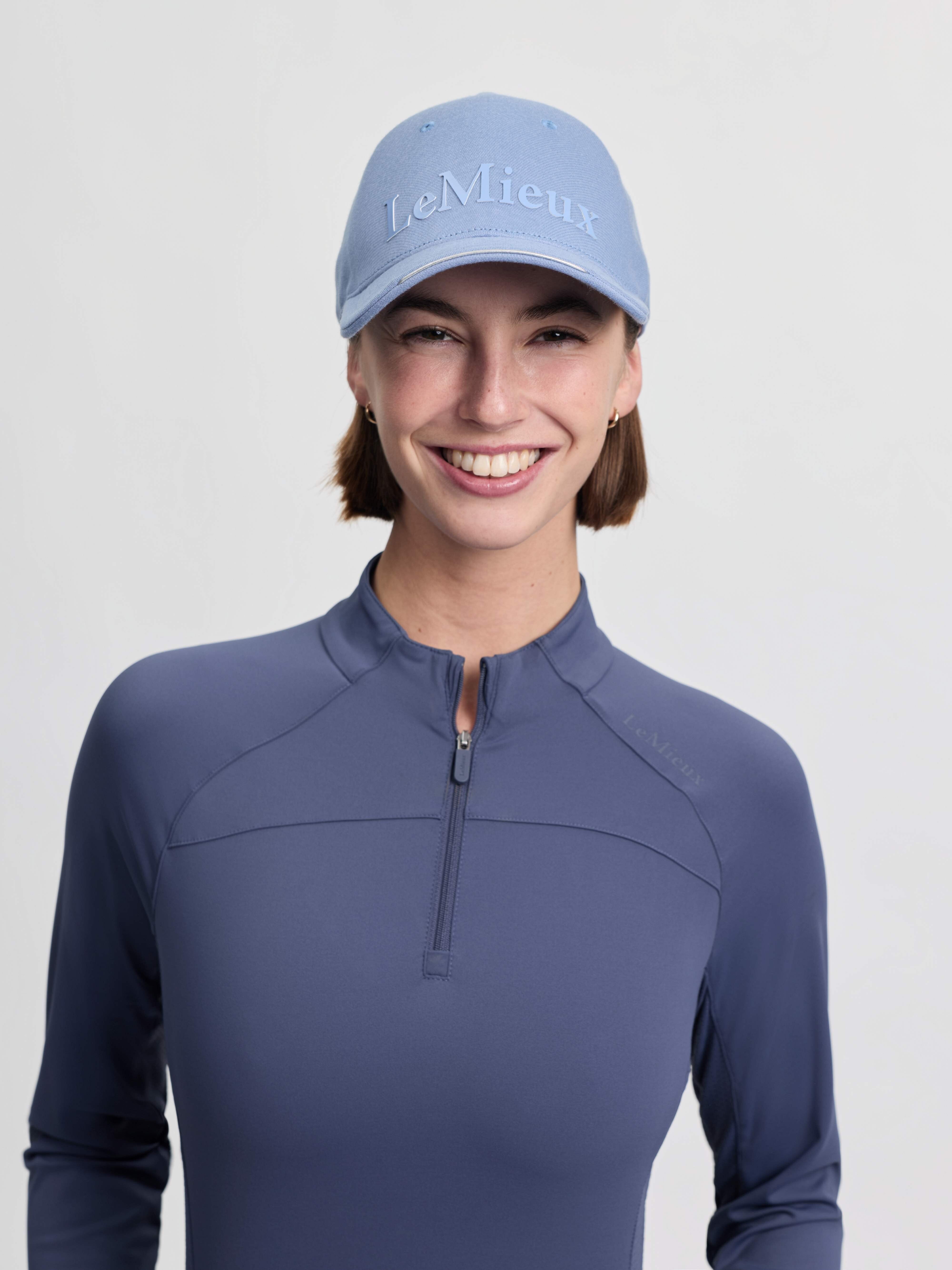 Front view of a female model wearing the powder blue LeMieux Lara Cap on a plain background