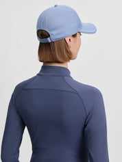 Back view of a female model wearing the powder blue LeMieux Lara Cap on a plain background