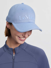 Front view of a female model wearing the powder blue LeMieux Lara Cap on a plain background