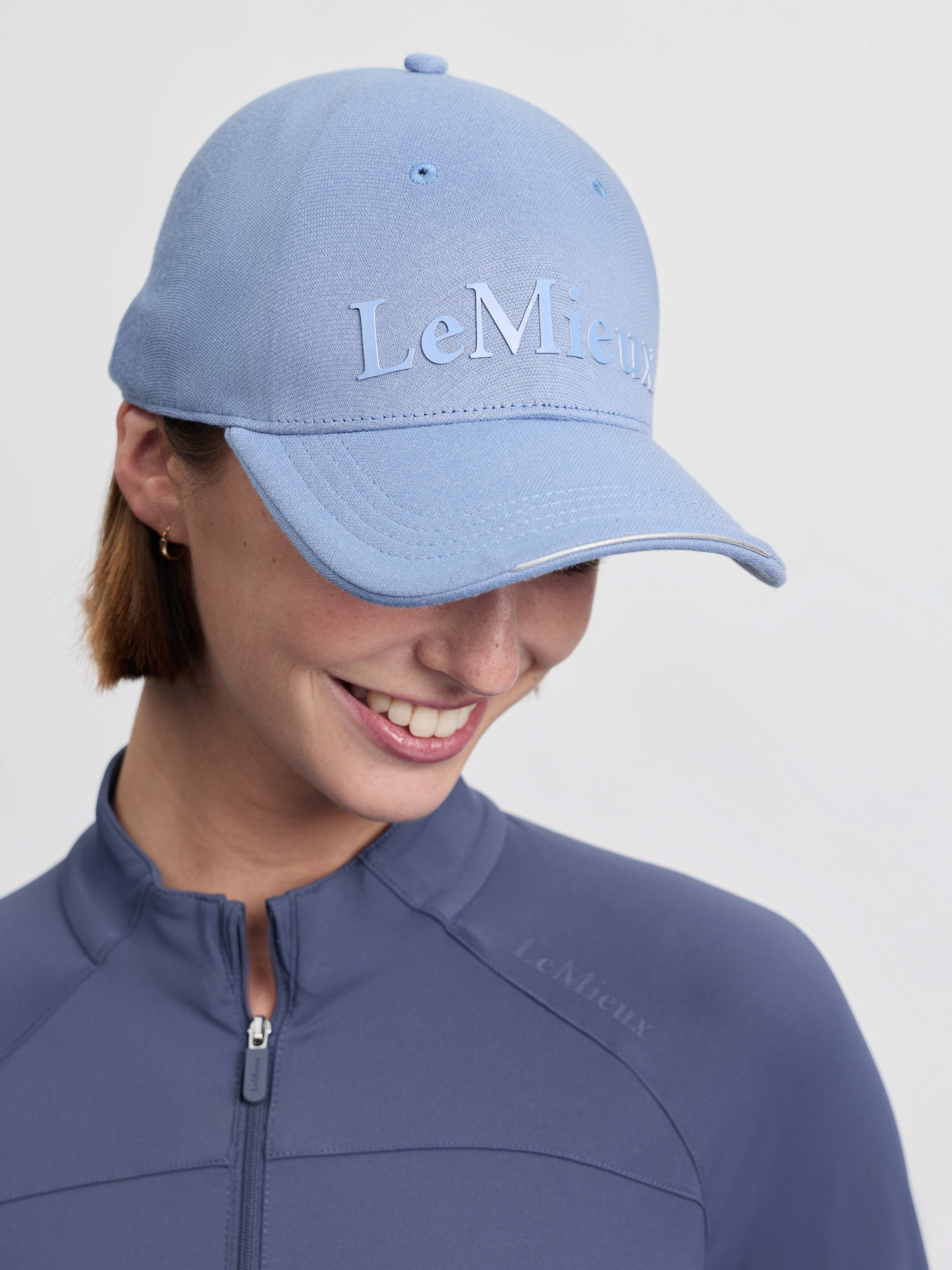 Front view of a female model wearing the powder blue LeMieux Lara Cap on a plain background