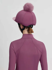Back view of a female model wearing the dark pink LeMieux Classique Pom Hat Silk on a plain background