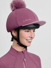 Side view of a female model wearing the dark pink LeMieux Classique Pom Hat Silk on a plain background