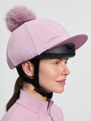 Side view of a female model wearing the pink LeMieux Classique Pom Hat Silk on a plain background