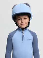 Front view of a young male model wearing the Powder Blue LeMieux Mini Double Pom Hat Silk on a plain background