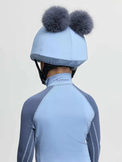 Back view of a young male model wearing the Powder Blue LeMieux Mini Double Pom Hat Silk on a plain background