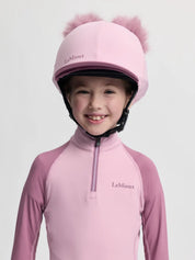 Front view of a young female model wearing the Fondant LeMieux Mini Double Pom Hat Silk on a plain background