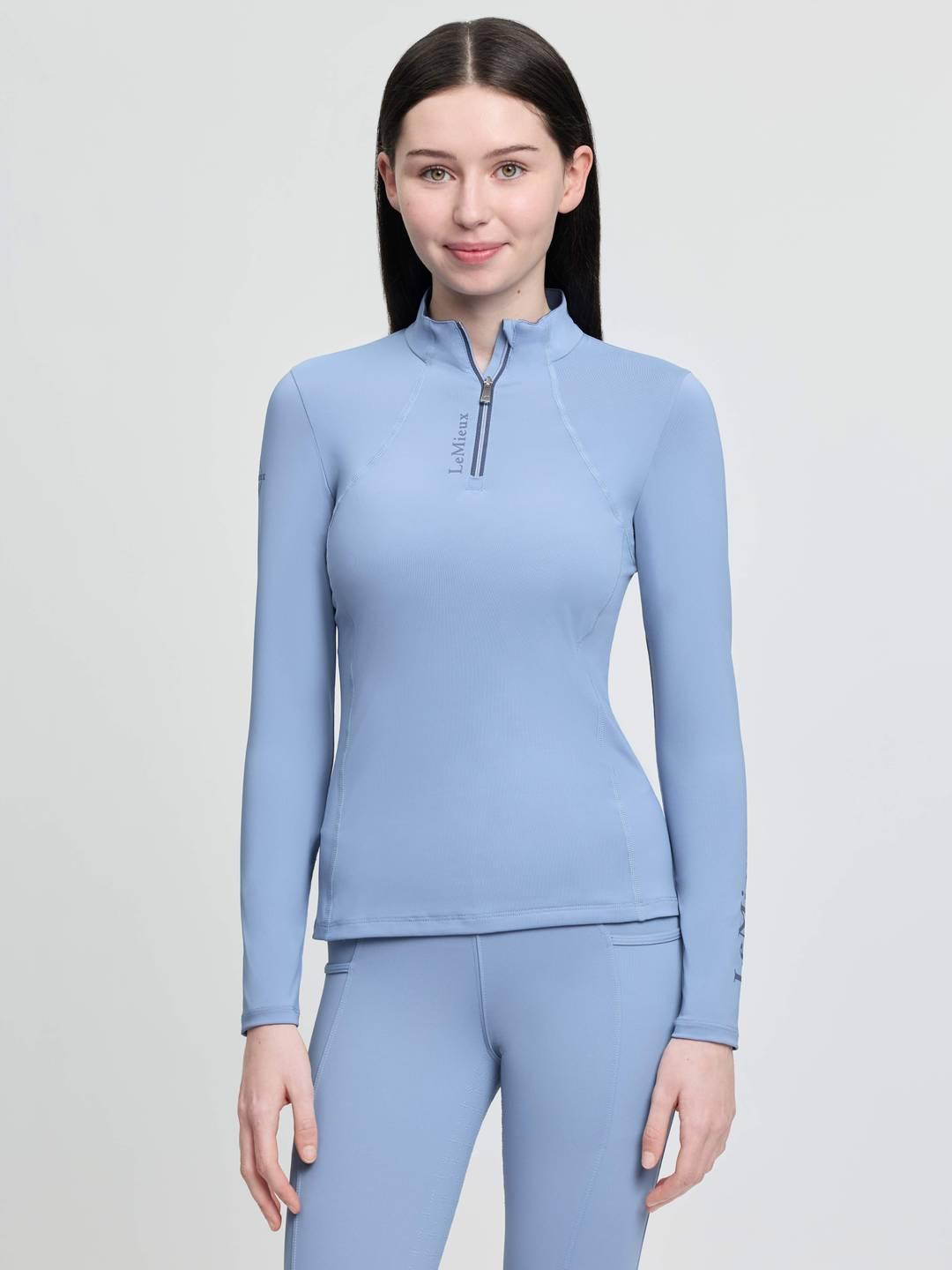 Front view of a young female model wearing the powder blue LeMieux Young Rider Classique Base Layer on a plain background