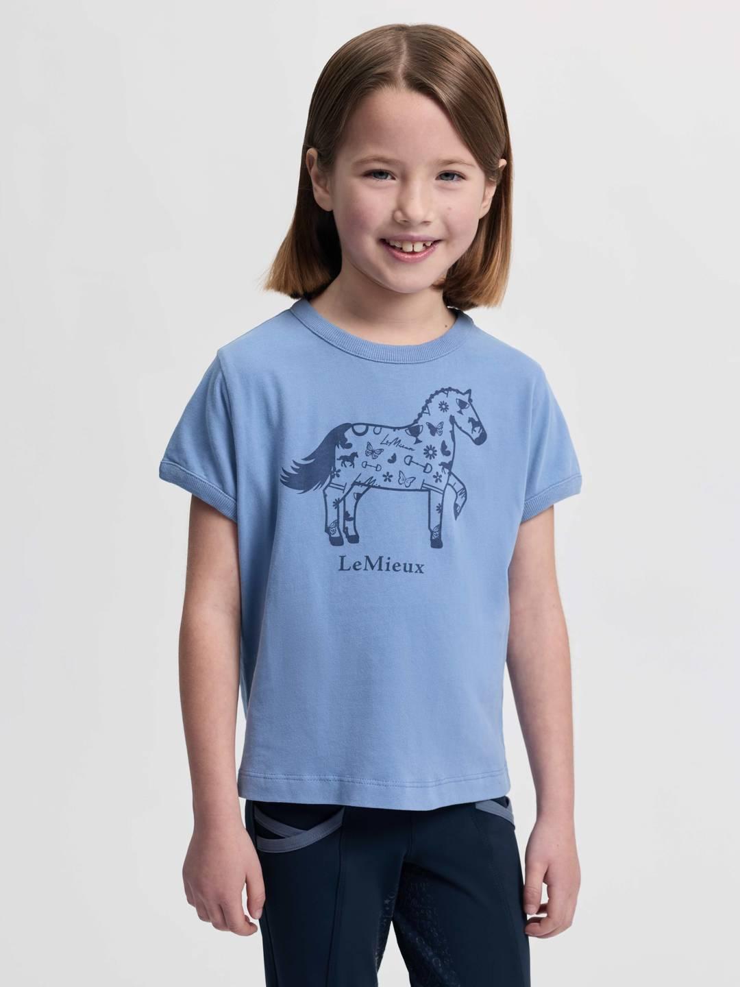 Front view of a young female model wearing the powder blue LeMieux Mini Alex T-Shirt on a plain background