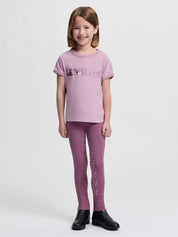 Full body front view of a young female model wearing the fondant LeMieux Mini Alex T-Shirt and purple tights on a plain background