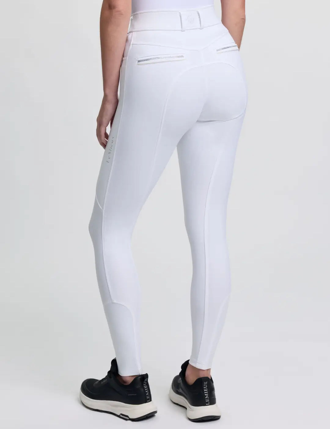 Back view of a model wearing the white LeMieux Brilliance Full Seat Breeches on a plain background