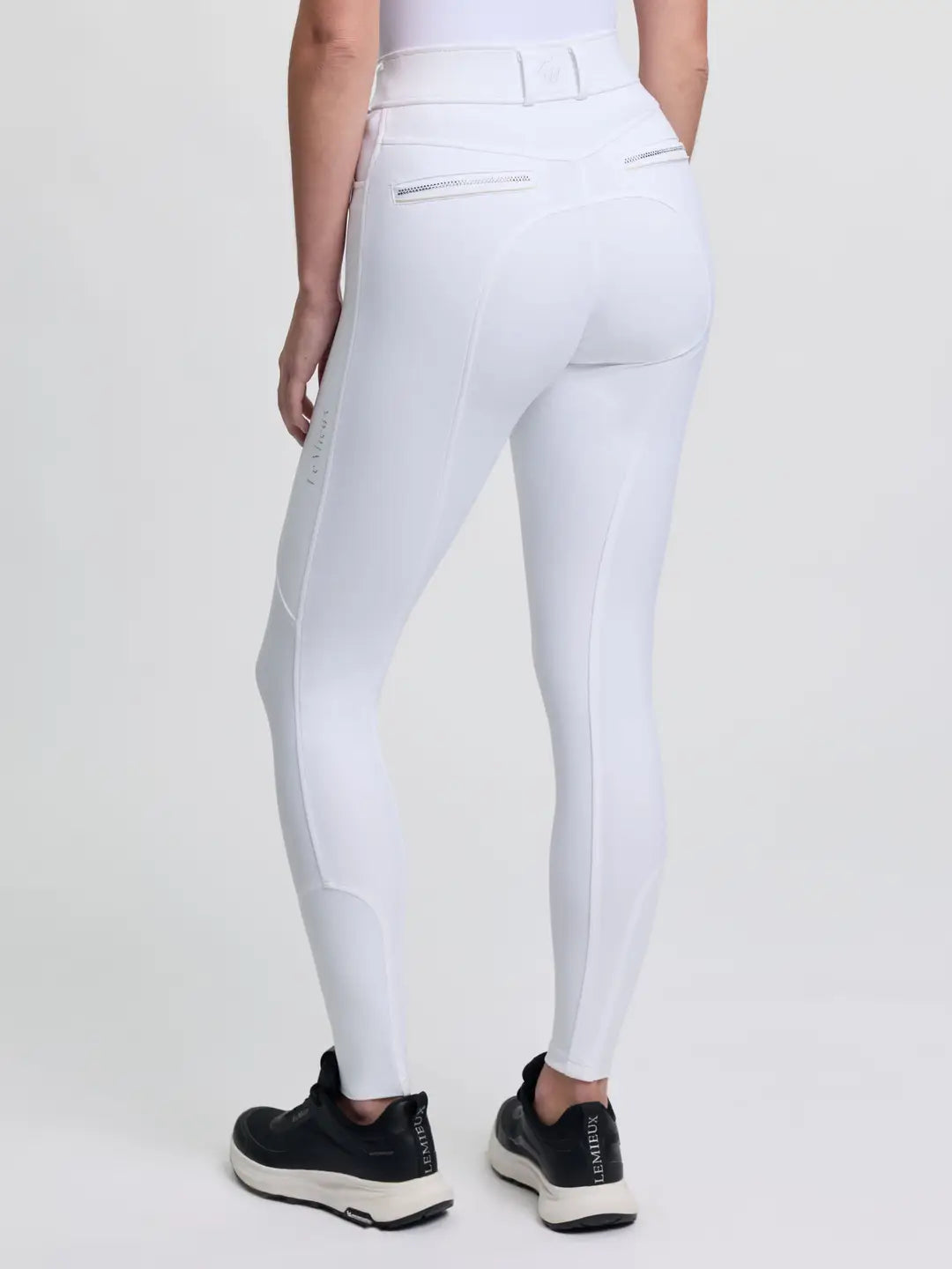 Back view of a model wearing the white LeMieux Brilliance Full Seat Breeches on a plain background