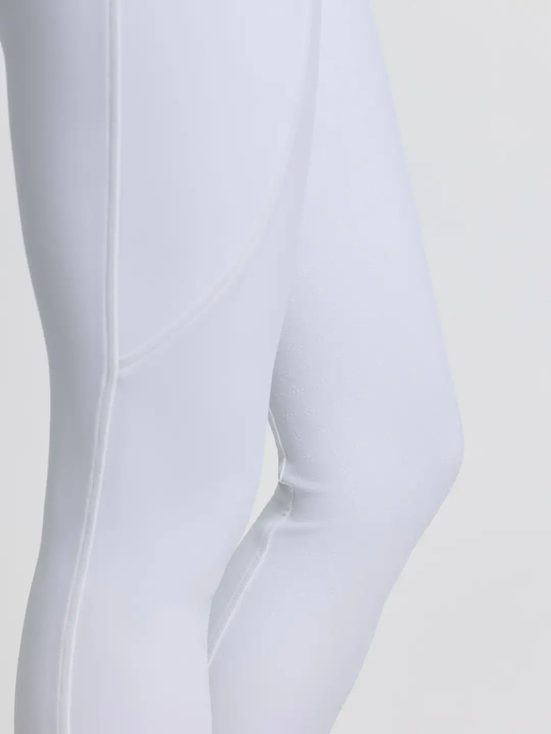 Close-up side view of a model wearing the white LeMieux Brilliance Full Seat Breeches on a plain background