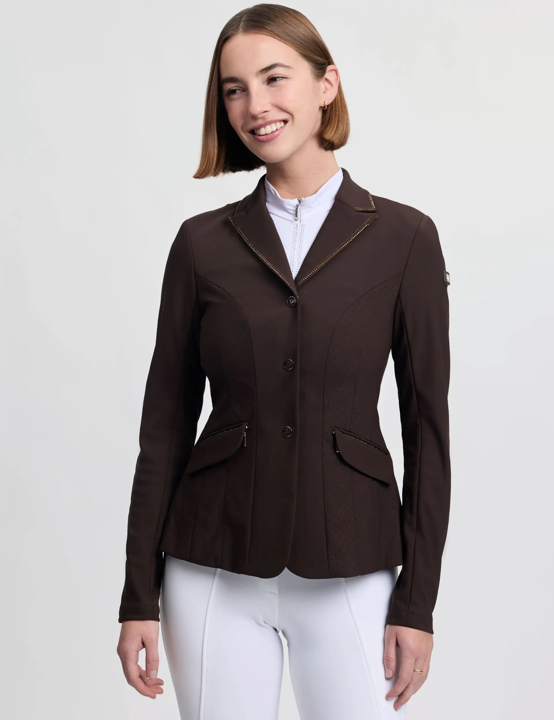 Front view of a female model wearing the brown LeMieux Brilliance Diana Show Jacket on a plain background