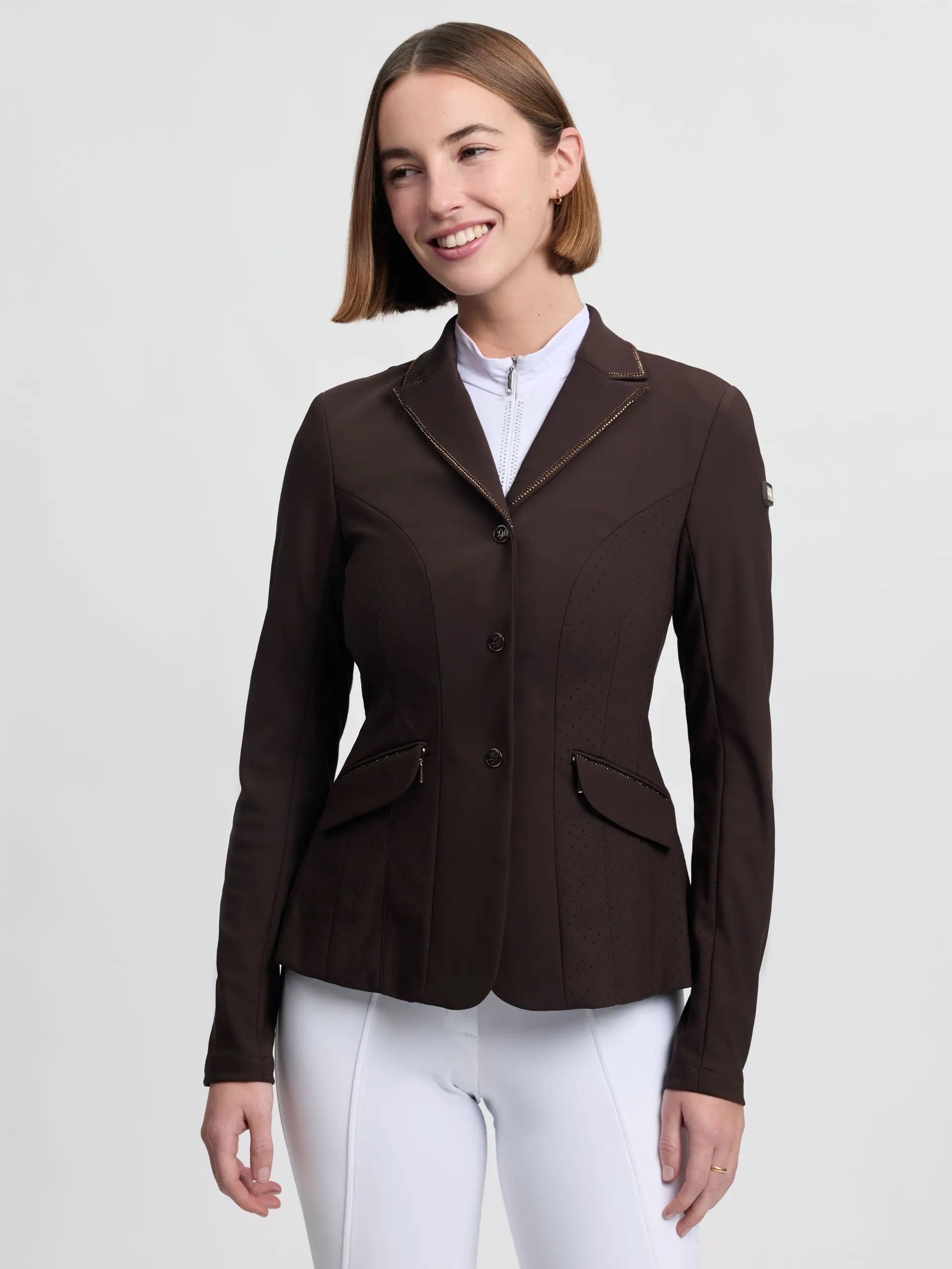 Front view of a female model wearing the brown LeMieux Brilliance Diana Show Jacket on a plain background