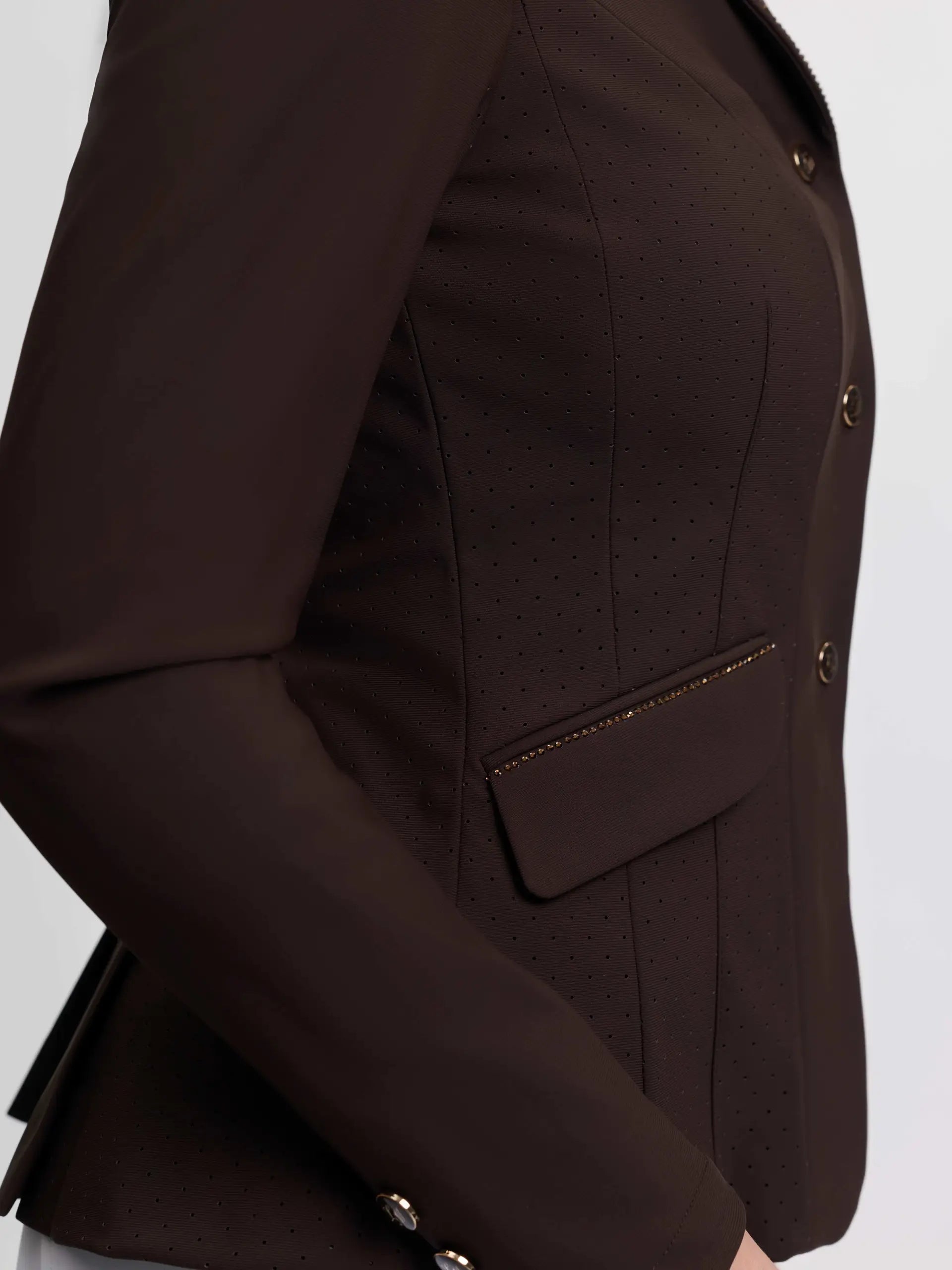 Close-up side view of a model wearing the brown LeMieux Brilliance Diana Show Jacket on a plain background