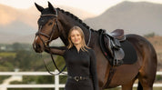 Front view of a female model standing in front of a dark colored horse that is wearing the black LeMieux Air-Tek Mesh Close Contact Square Pad
