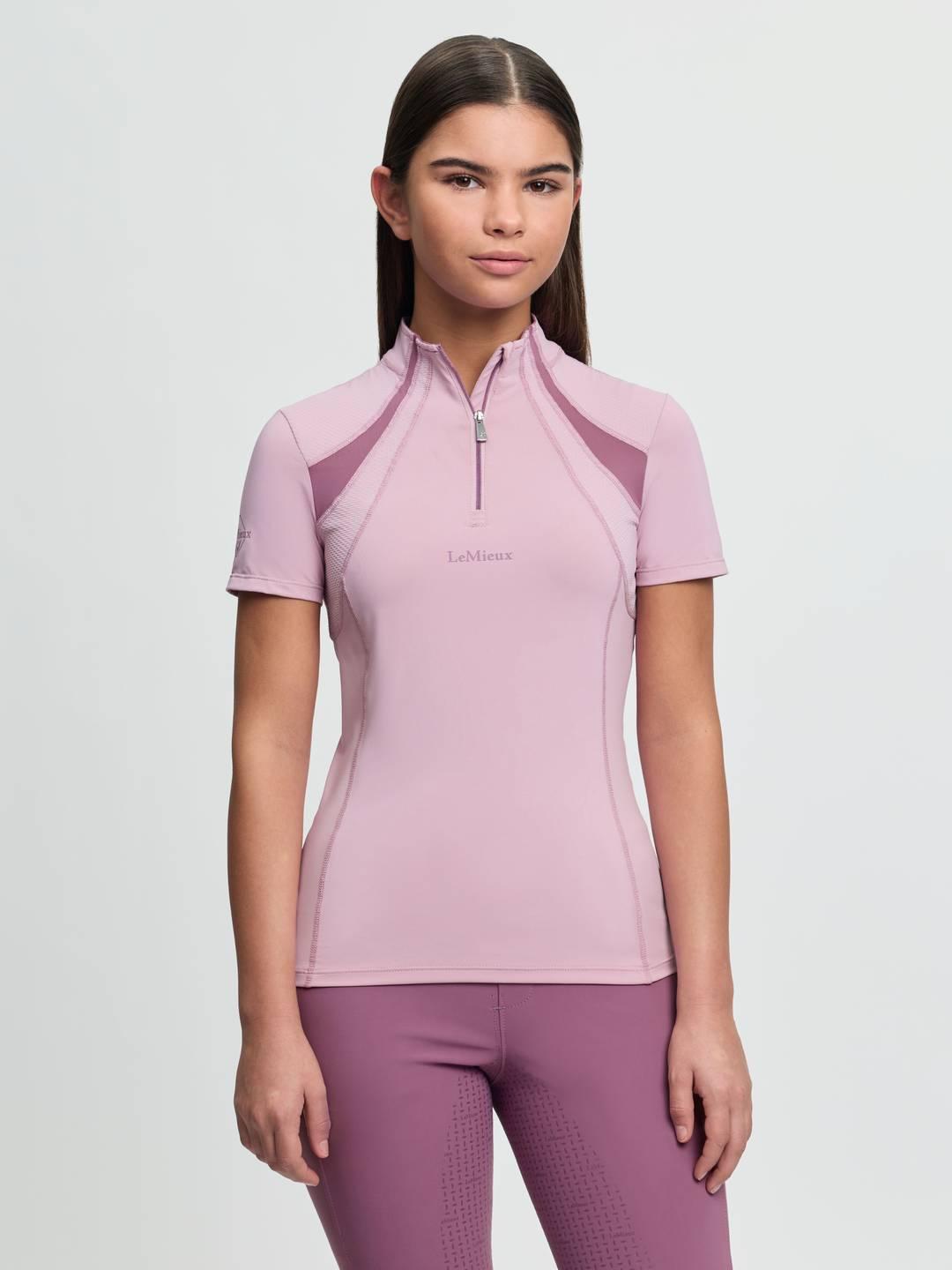 Front view of a young female model wearing the pink LeMieux Young Rider Mia Mesh Short Sleeve Base Layer on a plain background
