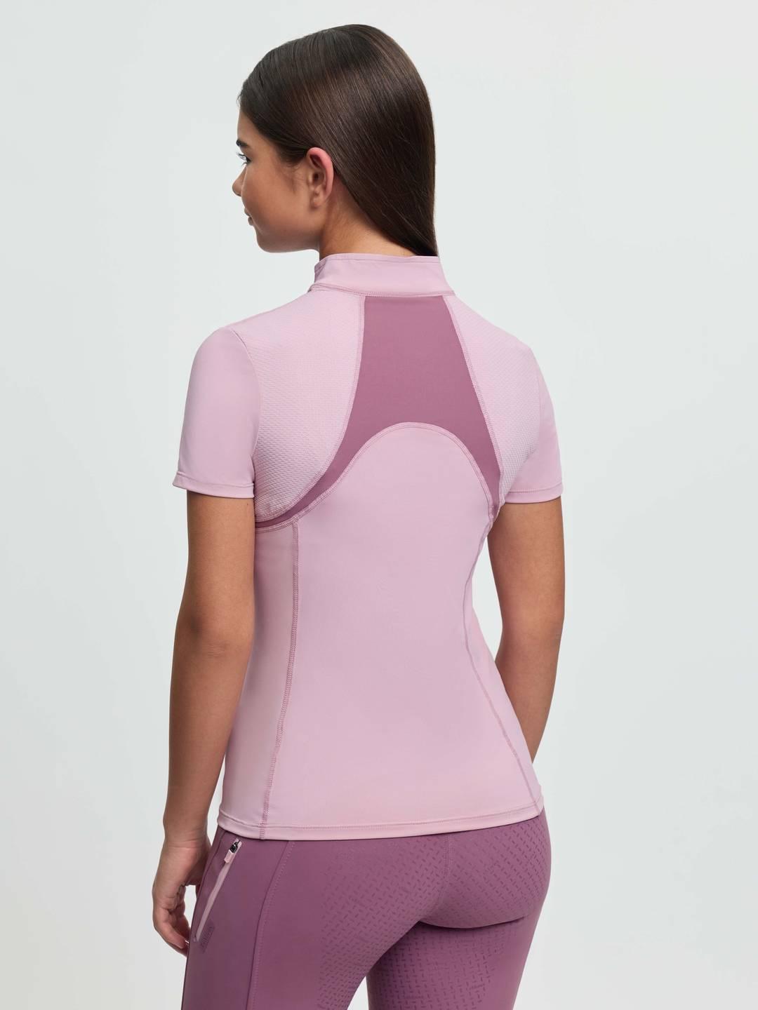 Back view of a young female model wearing the pink LeMieux Young Rider Mia Mesh Short Sleeve Base Layer on a plain background