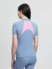 Back view of a young female model wearing the blue LeMieux Young Rider Mia Mesh Short Sleeve Base Layer on a plain background