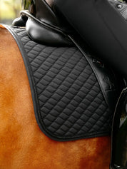 Close-up view of the quilting on the black LeMieux Brilliance Dressage Square worn by a chestnut horse