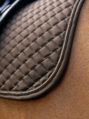 Close-up view of the quilting and piping detail on the brown LeMieux Brilliance Dressage Square
