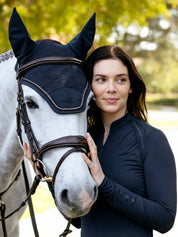 Front view of a gray horse wearing the navy LeMieux Brilliance Fly Hood while standing next to a female model