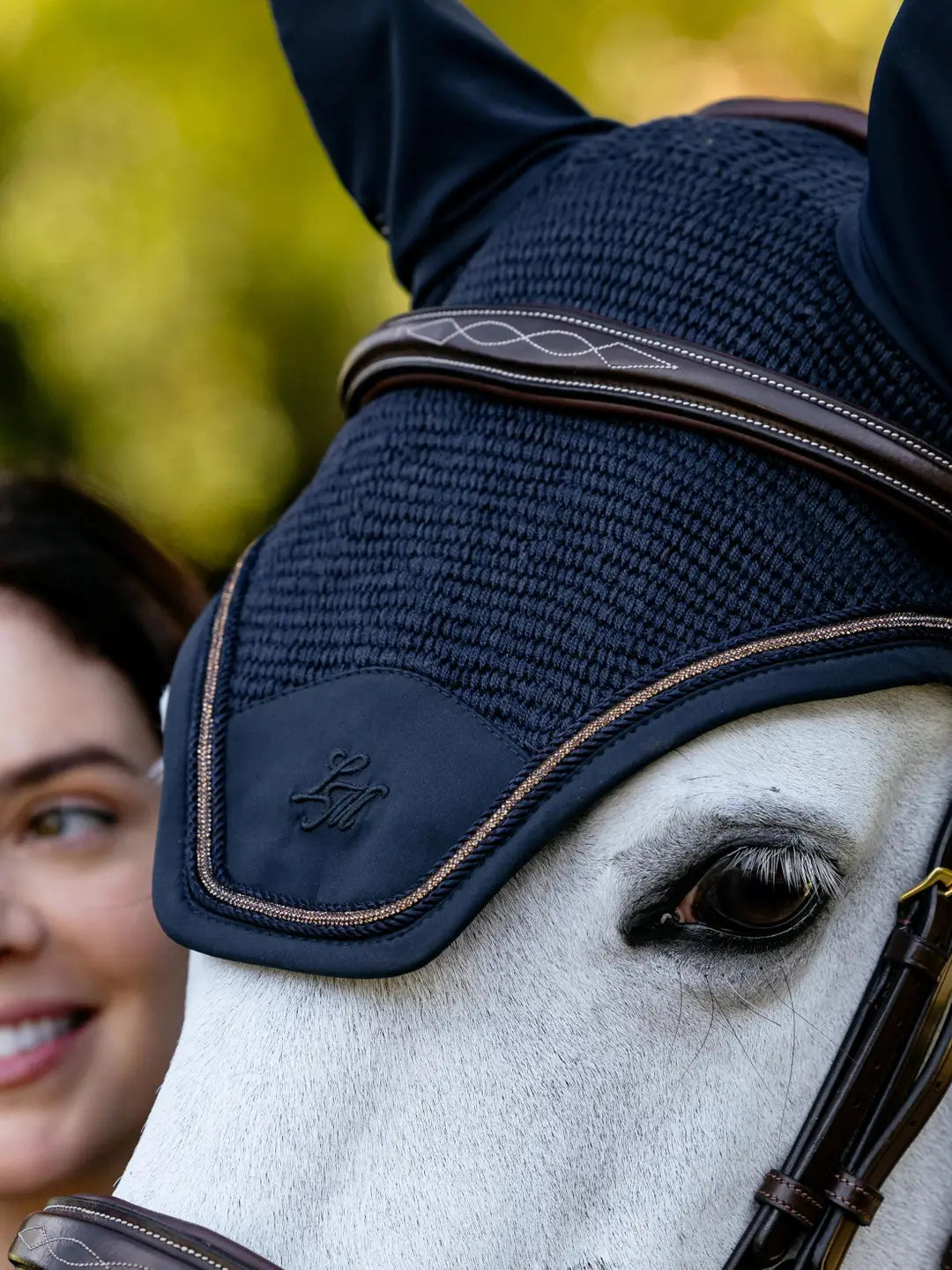 Close-up angled front view of a gray horse wearing the navy LeMieux Brilliance Fly Hood