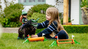 View of a young girl playing with the LeMieux Toy Pony XC Jump Set while sitting outside in the grass