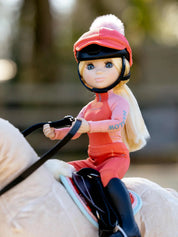 Angled front view of the coral Harlow LeMieux Toy Rider riding a toy pony