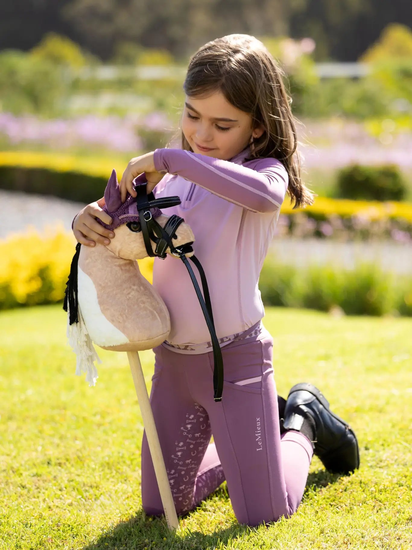 Child playing outside with a LeMieux Mini Hobby Horse in a buckskin paint color