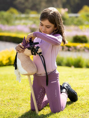 Child playing outside with a LeMieux Mini Hobby Horse in a buckskin paint color