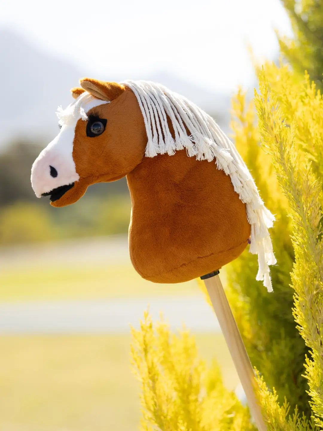 Side view of the LeMieux Mini Hobby Horse in a palomino color with white mane outside