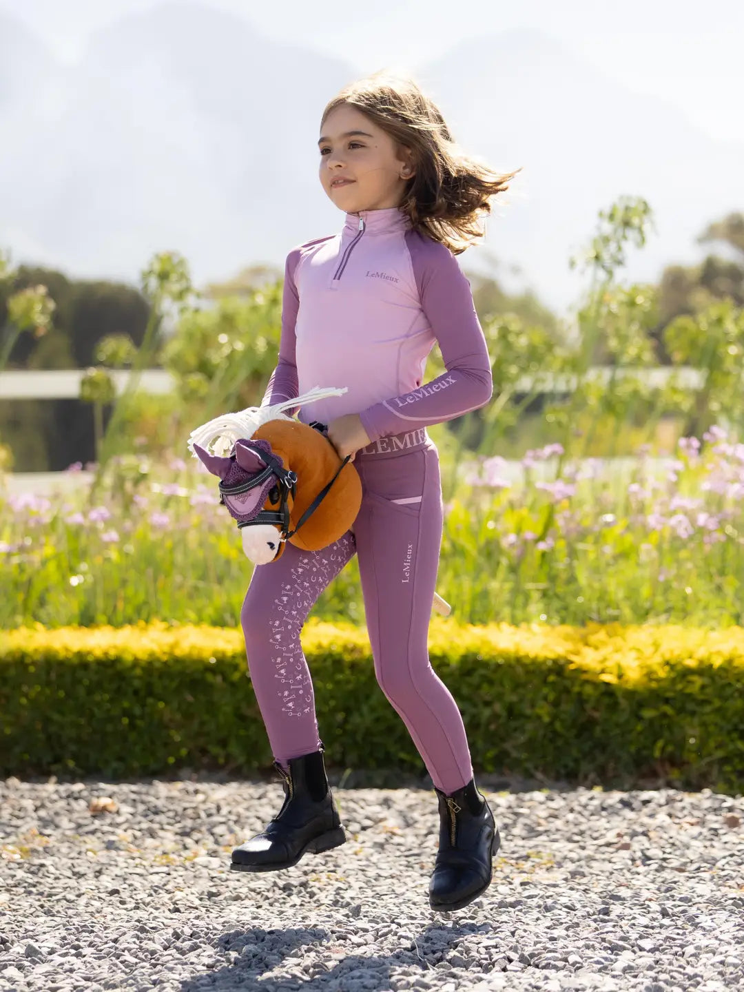 Child riding the LeMieux Mini Hobby Horse in a palomino color outside