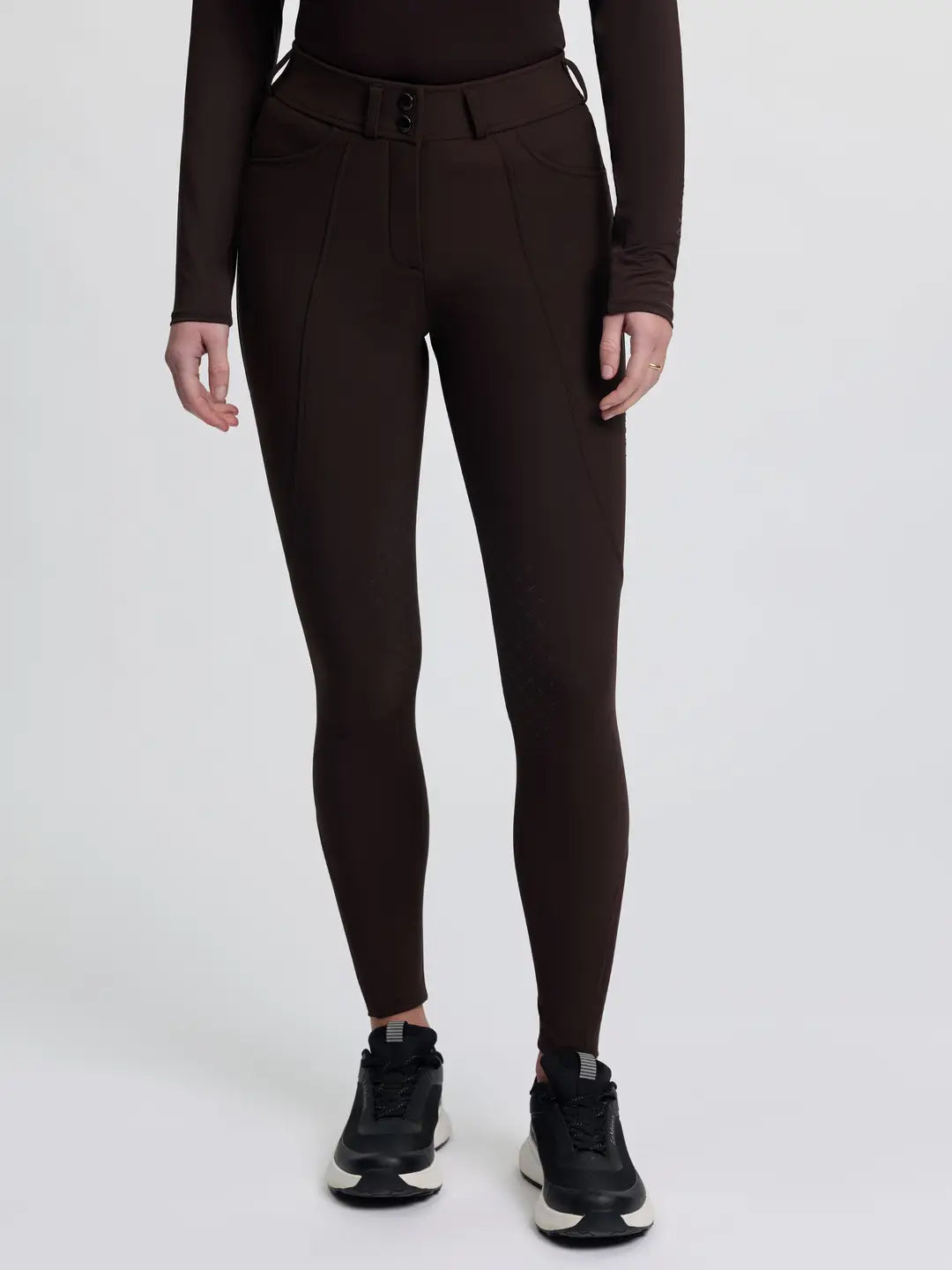 Front view of a model wearing the brown LeMieux Brilliance Knee Grip Breeches on a plain background