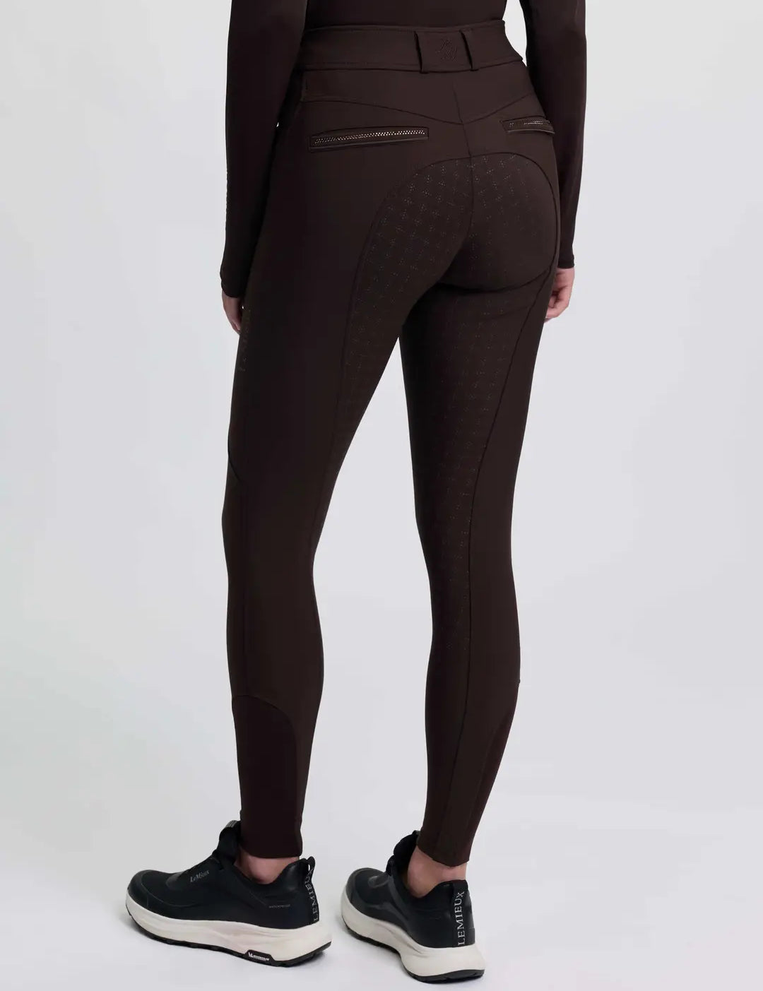 Back view of a model wearing the brown LeMieux Brilliance Full Seat Breeches on a plain background