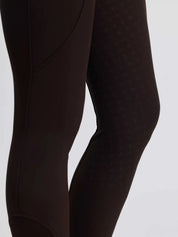 Close-up side view of the silicone grip on the brown LeMieux Brilliance Full Seat Breeches on a plain background