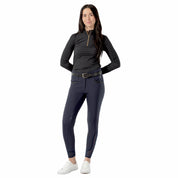 Full body view of a model wearing the navy Equinavia Kristina Full Seat Breeches, black top, and white shoes on a white background