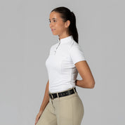 Side view of a female model wearing the white Horze Mina Short Sleeve Crystal Show Shirt on a plain background