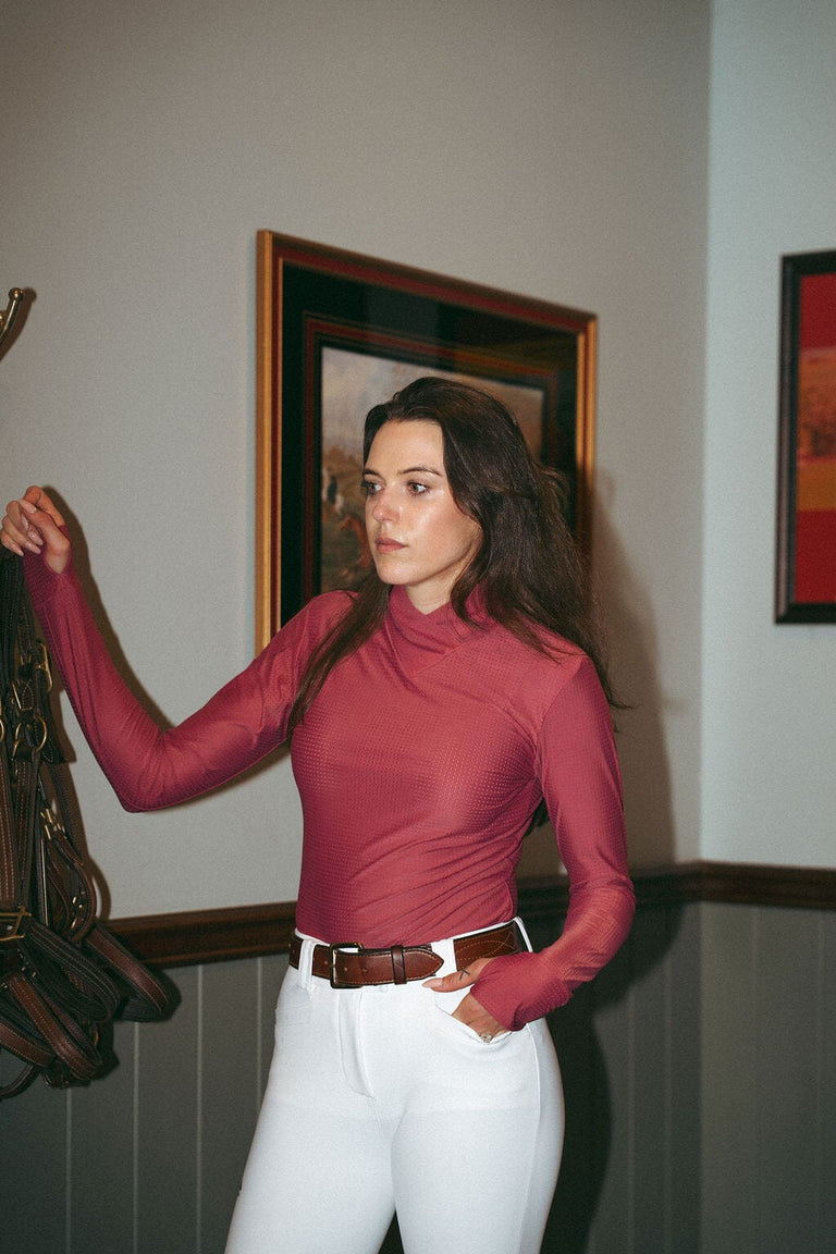 Front view of a female model wearing the cherry blossom Criniere Kai Shirt while standing in a tack room